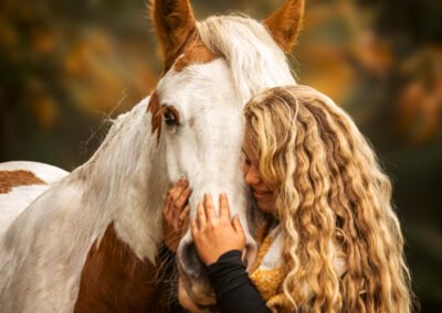 A girl hugging her piebald horse very dearly